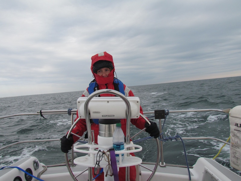 steering a sailboat wearing red foul weather gear