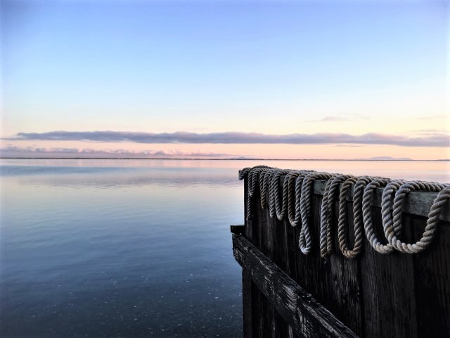 Image of rope draped on sea wall at sunrise.