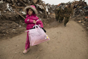 Image of small Japanese girl walking through piles of tsunami debris.