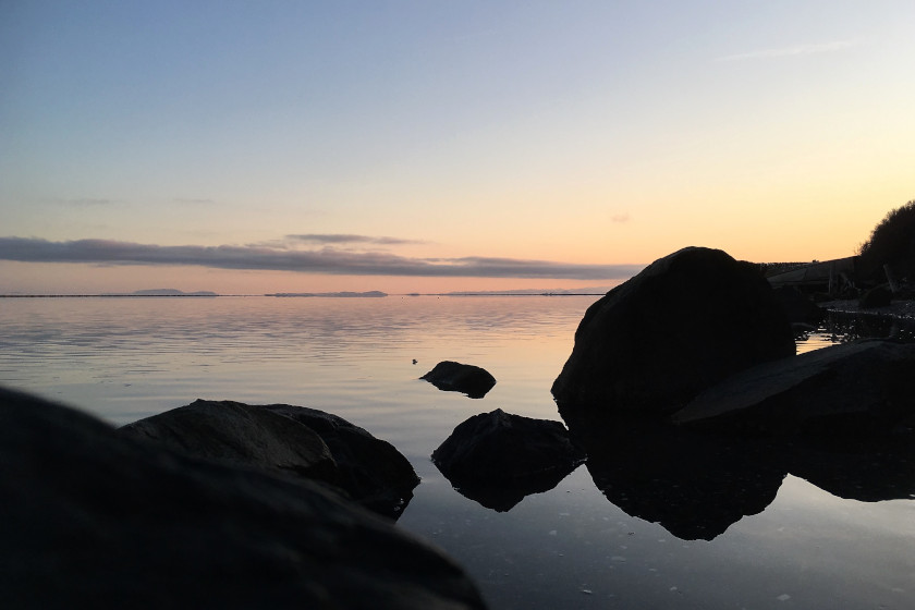Image of boulders and calm water at sunrise