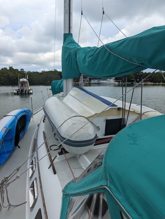 Dinghy stowed upside down on deck of sailboat.