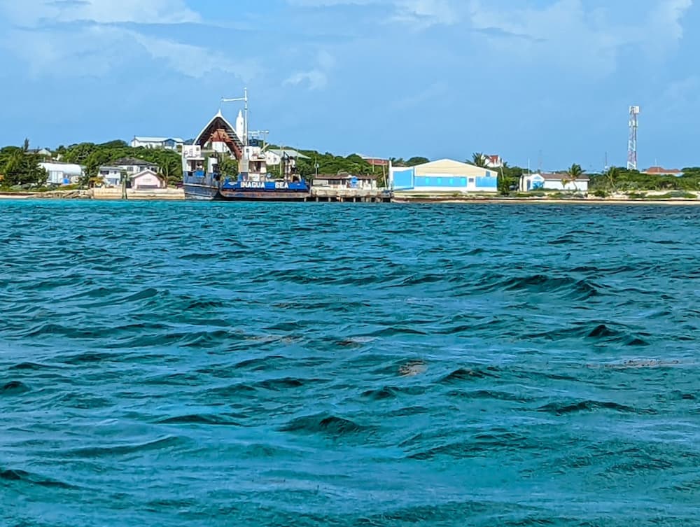 the waterfront at Clarence Town, Long Island, Bahamas including a blue ship with the bow raised